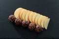 Eleven Peices of Sliced Apple and Five Nutty Chocolate Ice Cream Balls on a black Slated Serving Tray Royalty Free Stock Photo