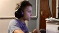 an eleven-year-old boy in headphones sits at the computer in the evening and plays games and studies