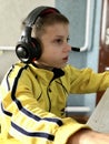 an eleven-year-old boy in headphones sits at the computer in the evening and plays games and studies