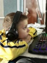 an eleven-year-old boy in headphones sits at the computer in the evening and plays games and studies