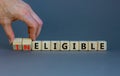 Eligible or ineligible symbol. Businessman turns wooden cubes and changes words Ineligible to Eligible. Beautiful grey table grey Royalty Free Stock Photo