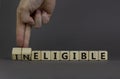 Eligible or ineligible symbol. Businessman turns wooden cubes and changes words Ineligible to Eligible. Beautiful grey table grey Royalty Free Stock Photo