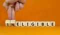 Eligible or ineligible symbol. Businessman turns wooden cubes and changes words Ineligible to Eligible. Beautiful orange table Royalty Free Stock Photo