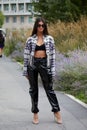 Elisa Maino with black, shiny plastic trousers and open checkered shirt before MSGM fashion