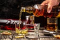 Elite drink for masculine relaxation. A man`s hand pours a drink in a glass whiskey, rum ice on black background, copy space.