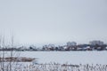Ellings near frozen river against backdrop of town of Ukrainka. Dry reeds by water. Winter landscape. Royalty Free Stock Photo