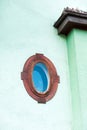 Ellipse shaped window in red wooden frame on multicolored green