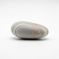 Elliptical gray stone with subtle beige striations resting on a plain Royalty Free Stock Photo
