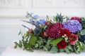 Elongated floral arrangement in vintage metal vase. table setting. Blue and red color. Gorgeous bouquet of different