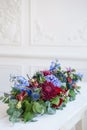 Elongated floral arrangement in vintage metal vase. table setting. Blue and red color. Gorgeous bouquet of different