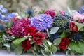 Elongated floral arrangement in vintage metal vase. table setting. Blue and red color. Gorgeous bouquet of different