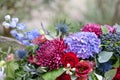 Elongated floral arrangement in vintage metal vase. table setting. Blue and red color. Gorgeous bouquet of different