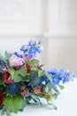 Elongated floral arrangement in vintage metal vase. table setting. Blue and red color. Gorgeous bouquet of different