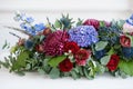 Elongated floral arrangement in vintage metal vase. table setting. Blue and red color. Gorgeous bouquet of different