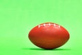 Elongated football sitting at ground level with green background.