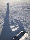 an elongated shadow of a skier on the snow of a ski slope