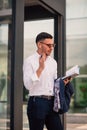 An eloquent businessman is outside, he is enjoying in the beautiful weather while looking at the notebook. Urban businessman Royalty Free Stock Photo