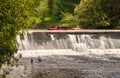 Elora, Ontario, Canada - 05 15 2022: Rowers in bright red kayaks look at geese behind waterfalls of the Grand River near