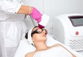 Elos epilation hair removal procedure on the face of a woman. Beautician doing laser rejuvenation on the forehead in a beauty Royalty Free Stock Photo