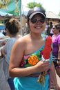 Smiling young woman holds elote or Mexican street corn at Latino Hispanic street fair food festival in Chicago.