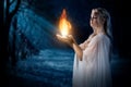 Elven girl holding fire in palms at night forest Royalty Free Stock Photo