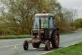 Ely, Cambridgeshire-UK: April 2023: Old, rusty Ford 4600 tractor being driven on a busy road. Royalty Free Stock Photo