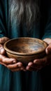 Emaciated hands hold an empty bowl against wood, depicting the reality of hunger