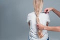 Emale hairdresser hold in hand between fingers lock of blonde hair, comb and scissors closeup. Image of hairdresser trimming ends