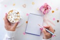 emale hands with a beautiful manicure write with a pen in a notebook and a white cup with coffee with marshmallows Royalty Free Stock Photo