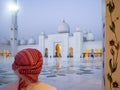 Emarati man looking at Sheikh Zayed Grand mosque at sunset in Abu Dhabi