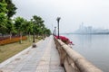 Embankment with flowers on the railing. Stone path along the river. Black lanterns, green trees, stone benches.