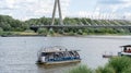 Embankment of the Vistula River in Warsaw. The ship is sailing. View of the bridge and the stadium. Sky with clouds.