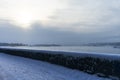 Embankment in winter. Dawn on the river. Winter river in the city. City embankment by the river on a sunny winter day with snow. Royalty Free Stock Photo