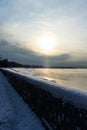 Embankment in winter. Dawn on the river. Winter river in the city. City embankment by the river on a sunny winter day with snow. Royalty Free Stock Photo