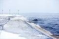 Embankment. Winter storm on the coast. Cold water and a pedestrian area near the water. Landscape with a promenade line near the l