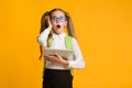 Embarassed Girl Clutching Head Using Tablet, Yellow Studio Background