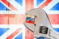 Embargo. Word on a wooden block in the colors of the Russian flag. Clamped wrench. Against the background of the flag of England.