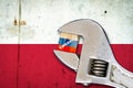 Embargo. Word on a wooden block in the colors of the Russian flag. Clamped wrench. Against the background of the flag of Poland.