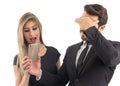 Embarrassed boyfriend shows the cell phone screen to his girlfriend. Couple sharing gossip..
