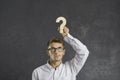 Embarrassed businessman with emotion of doubt on his face holding wooden question mark over his head