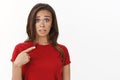 Embarrassed insecure cute brunette woman in red t-shirt look concerned and anxious, frowning upset pointing herself