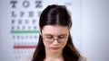 Embarrassed woman in broken eyeglasses looking down, feeling shame, bad vision