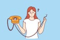 Embarrassed woman holding retro telephone with torn wire, and is wondering how to restore telephony