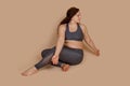 Embarrassed woman sitting on floor, looking side with open arms hands positions, half turn. Fitness gaining weight