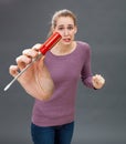 Embarrassed young woman showing screwdriver for DIY anxiety and stress