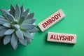 Embody Allyship symbol. Concept word Embody Allyship on wooden blocks. Beautiful green background with succulent plant. Business