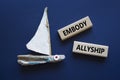 Embody Allyship symbol. Concept word Embody Allyship on wooden blocks. Beautiful deep blue background with boat. Business and