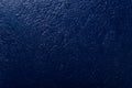 Embossed concrete wall painted in a deep blue shade of color. Abstract background for wallpaper