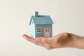 affordable housing dream: hand holding paper house on light background, Generative AI