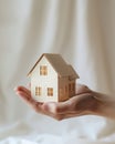 affordable housing dream: hand holding paper house on light background, Generative AI Royalty Free Stock Photo